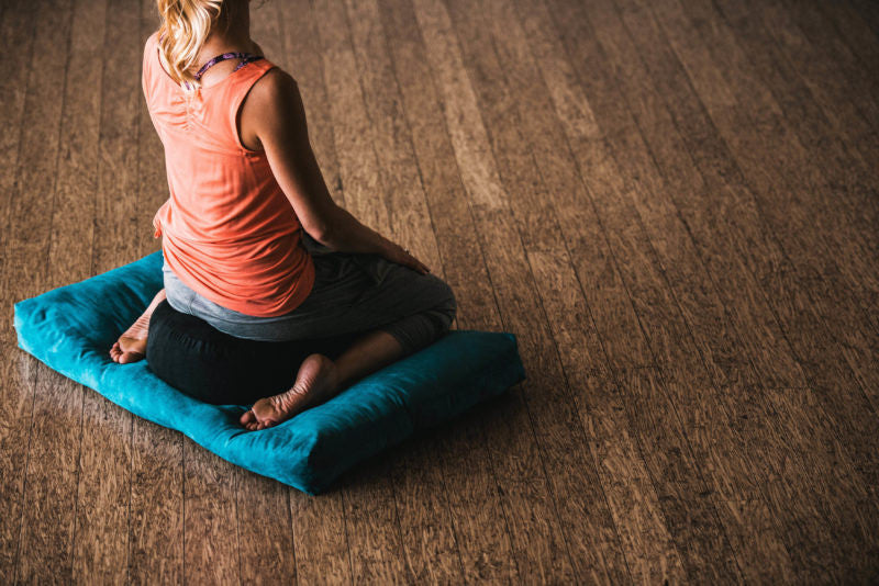woman meditating on 2 cushions