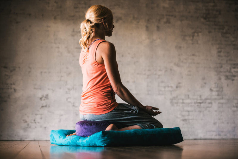 Woman sitting on a round and square meditation cushion