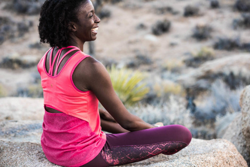 woman sitting outside on rock in yoga clothes