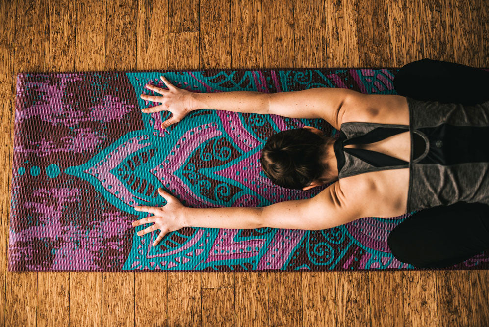 Woman in childs pose on colorful yoga mat