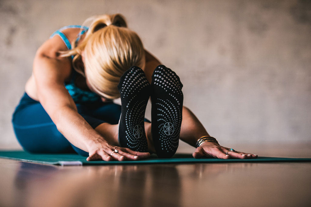 Woman in a forward fold wearing Gaiam yoga socks