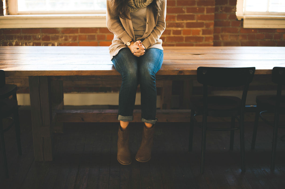 woman tightly clasping hands while sitting on a bench