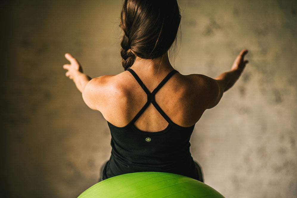 dark haired woman with braid does crunches on a balance ball
