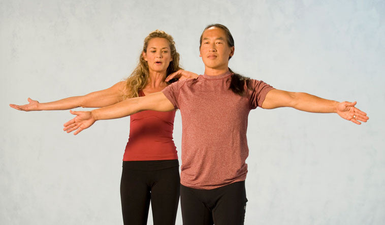 man and woman extend arms out to the side for yoga