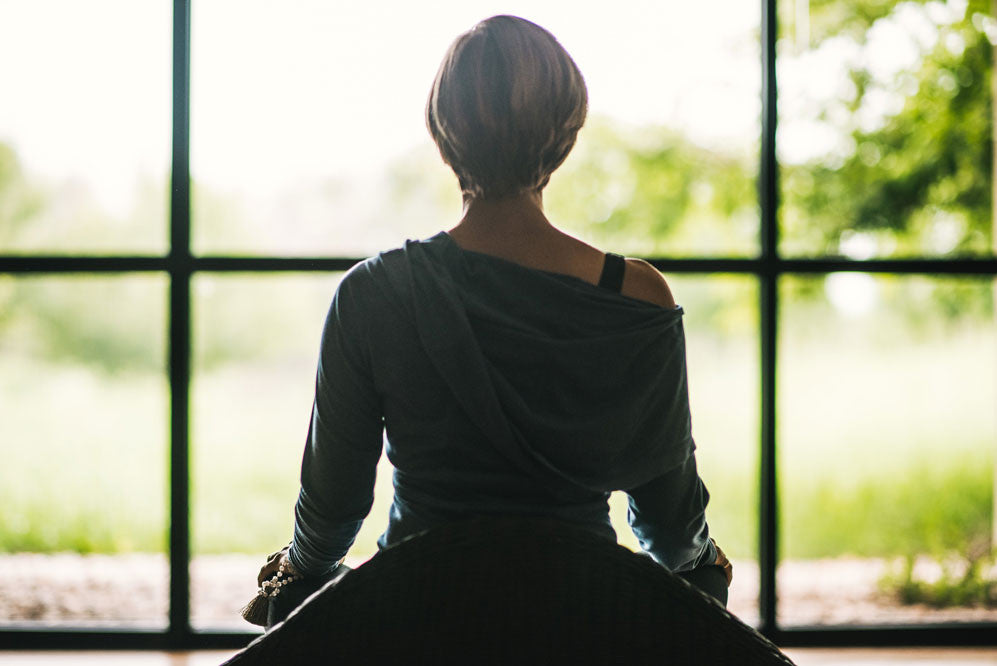 Woman sitting in front of window meditating