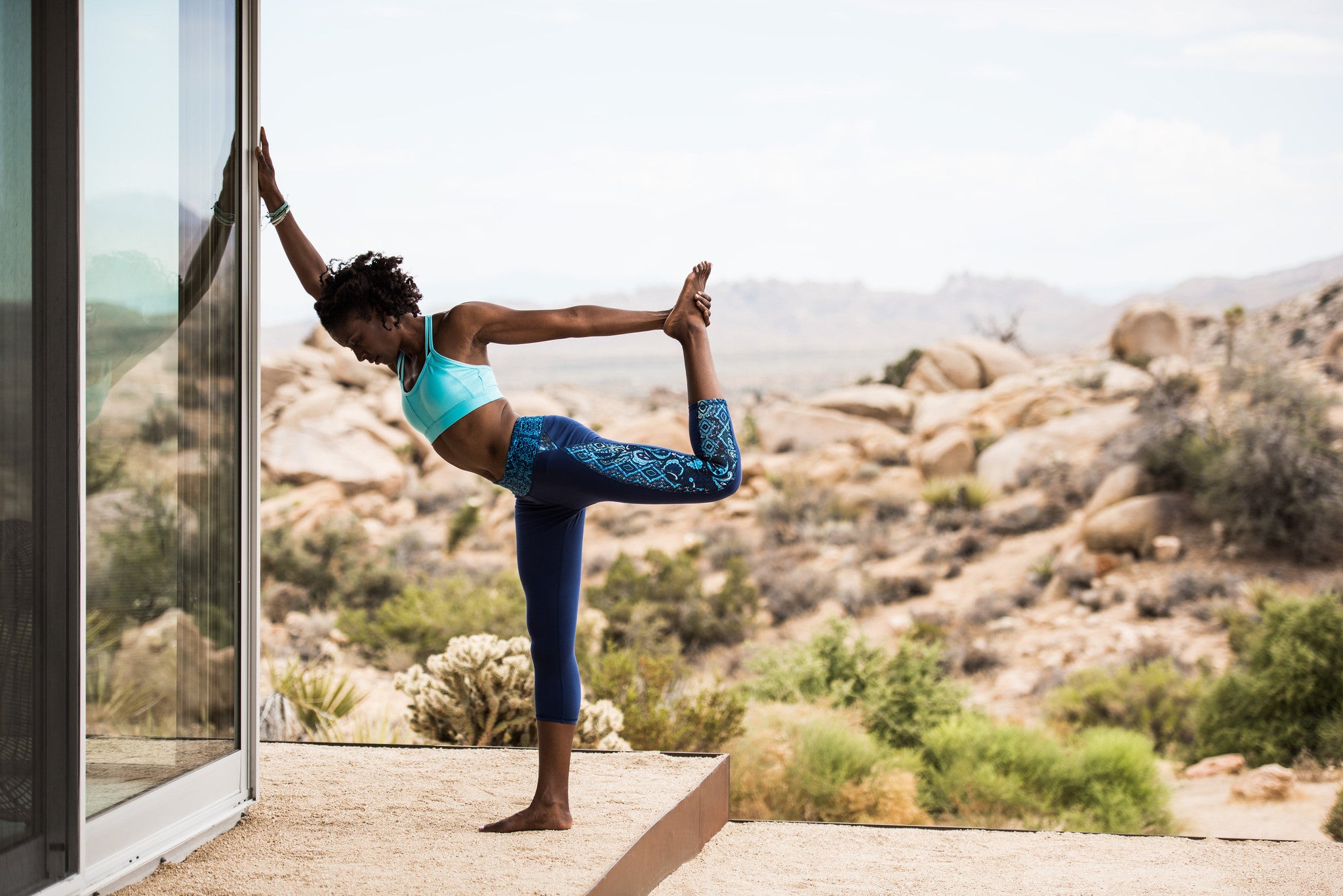 woman stretches quad while leaving up against window