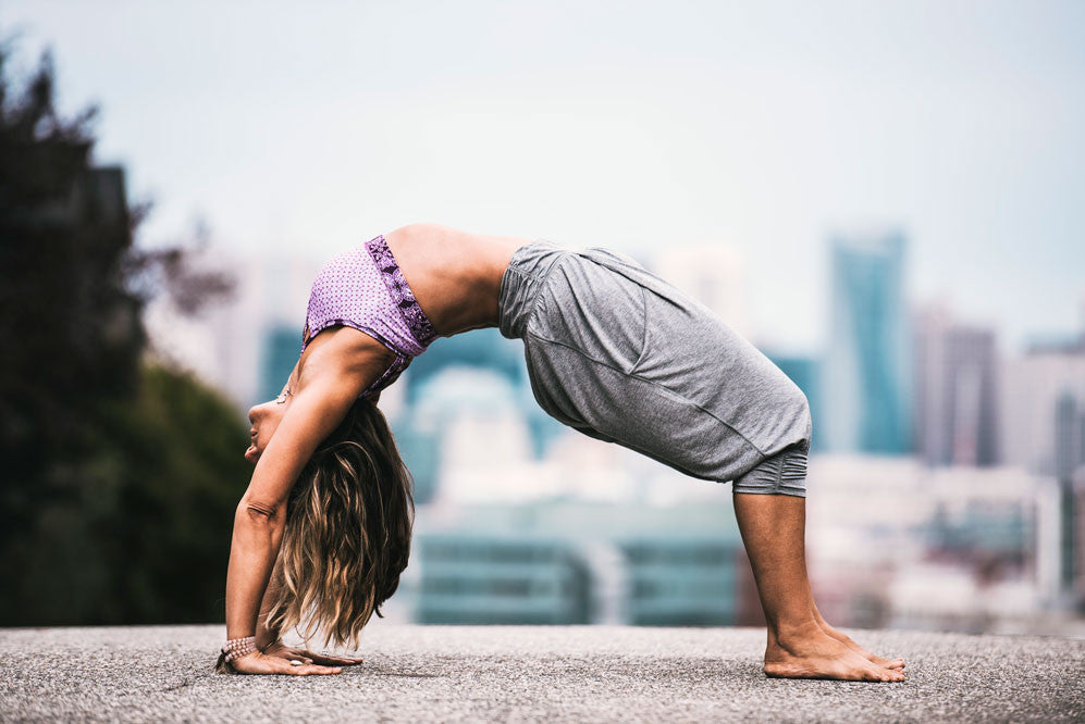 Barefoot woman does wheel pose in the street