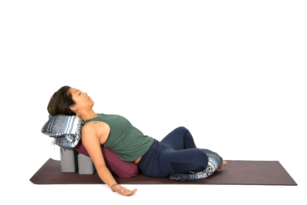 girl lays down on yoga props