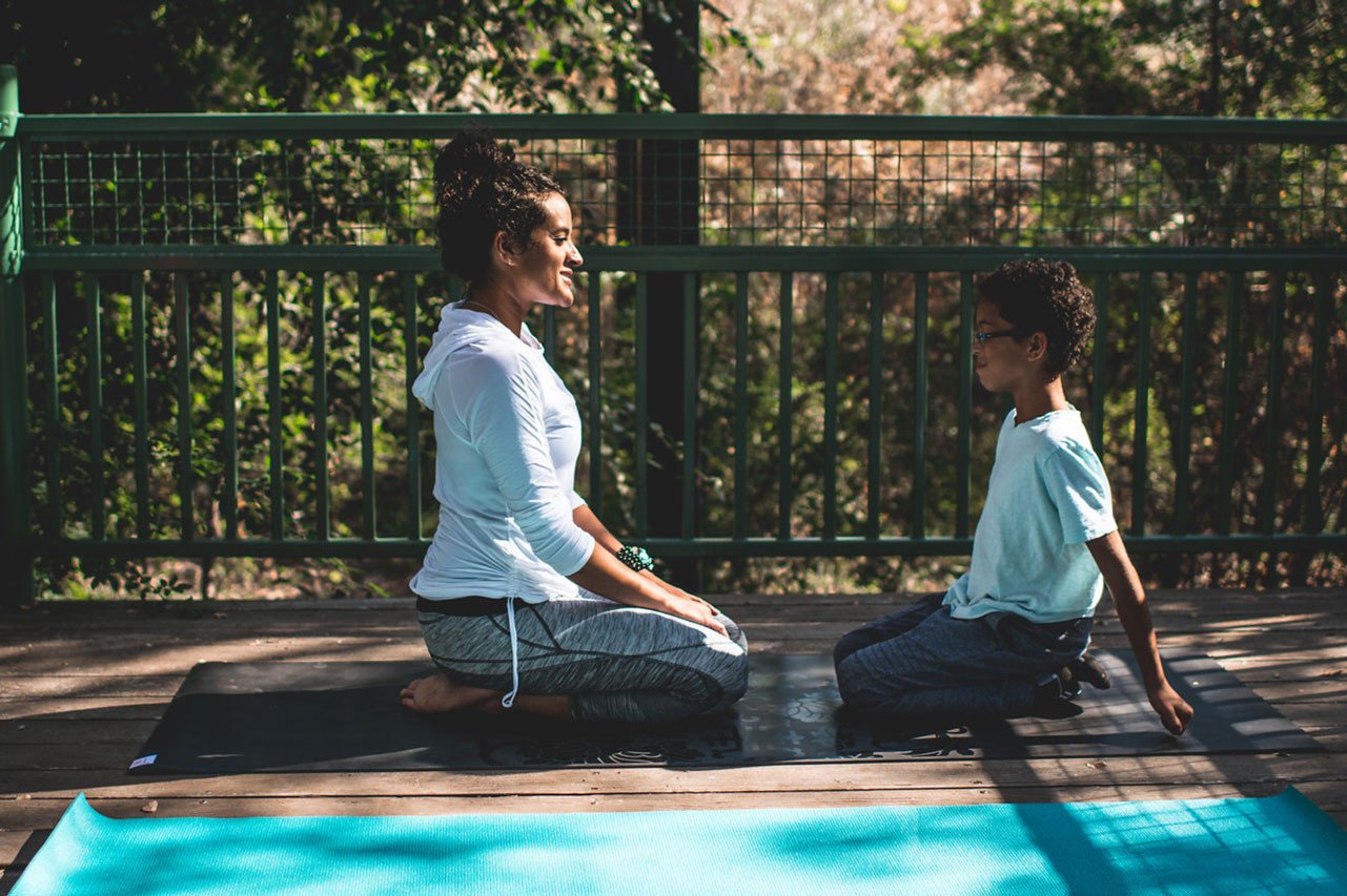 mom and son kneel outside on yoga mat