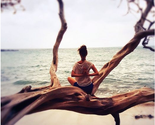 Woman sitting by the ocean with hands behind back