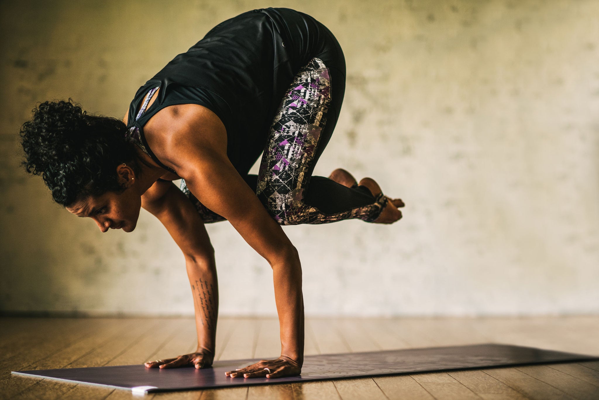 woman in crow pose on yoga mat