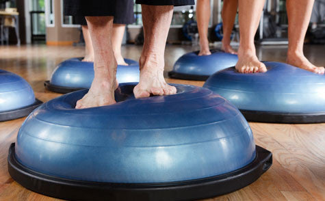People in fitness class standing on a balance disc
