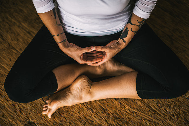 Person sitting in meditation position on the floor