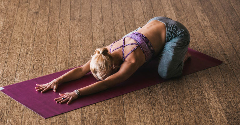 Woman on yoga mat in child's pose