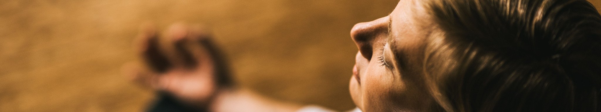Woman meditating with eyes closed and fingers in mudra.