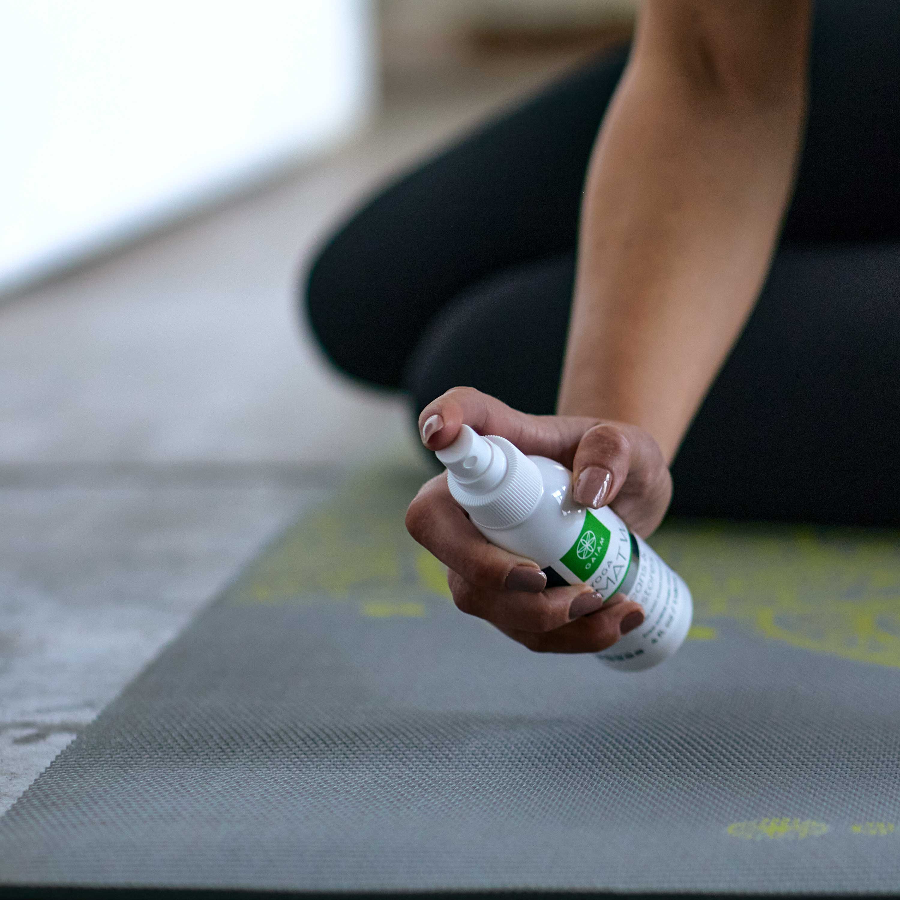 Person holding Yoga Mat Spray Wash. In position of getting ready to spray