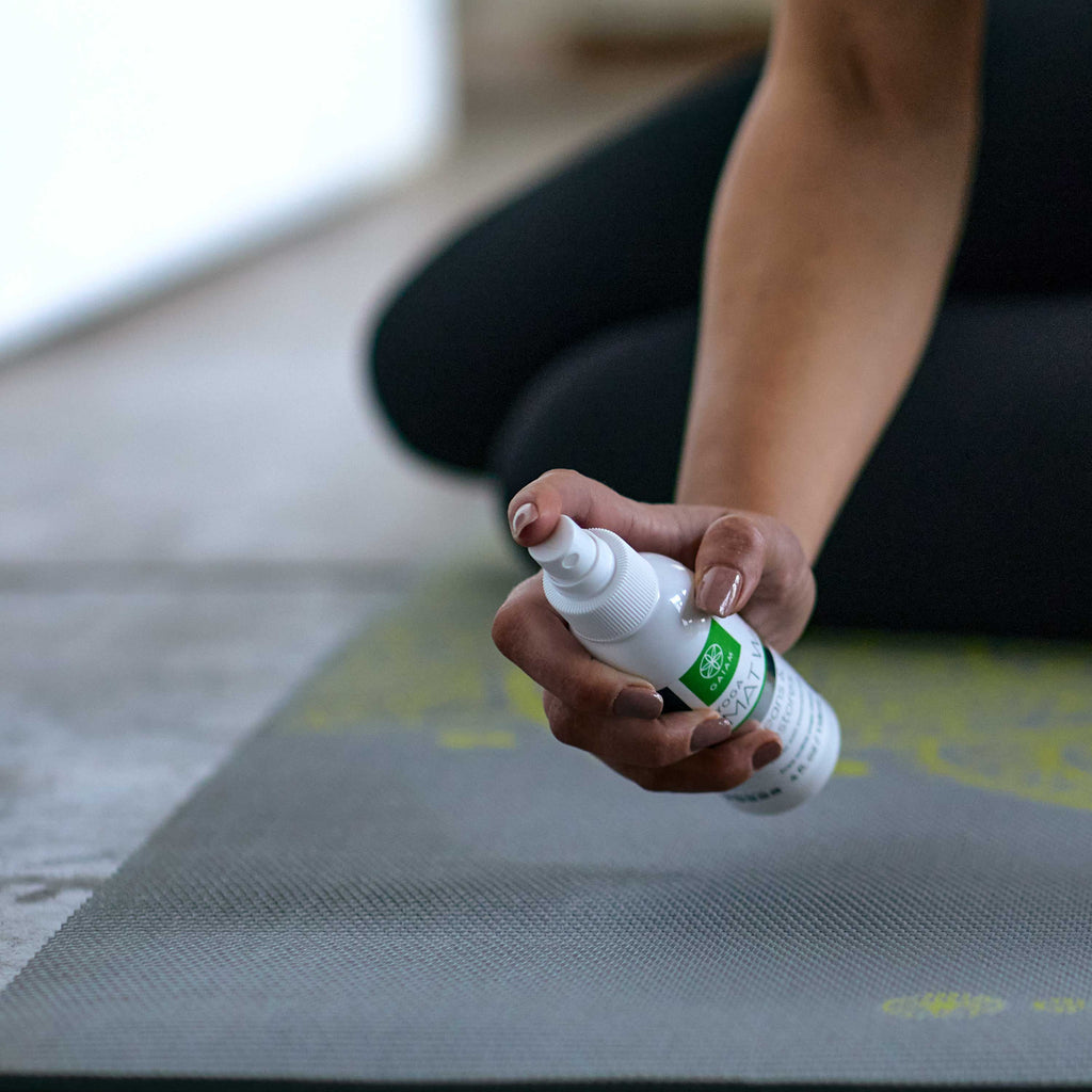 Person holding Yoga Mat Spray Wash.  In position of getting ready to spray 