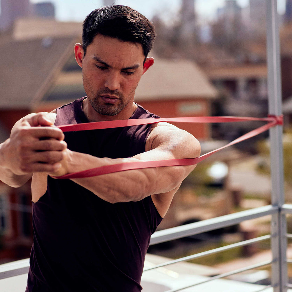 Super Band attached to a pole while man does shoulder rotations 