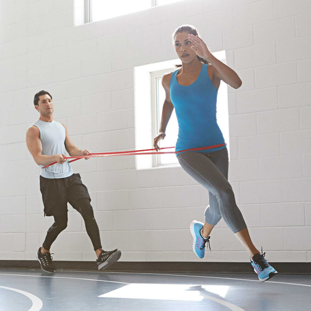 2 People - Super Band wrapped around each of their waists.  1st person is running creating resistance with the Band 