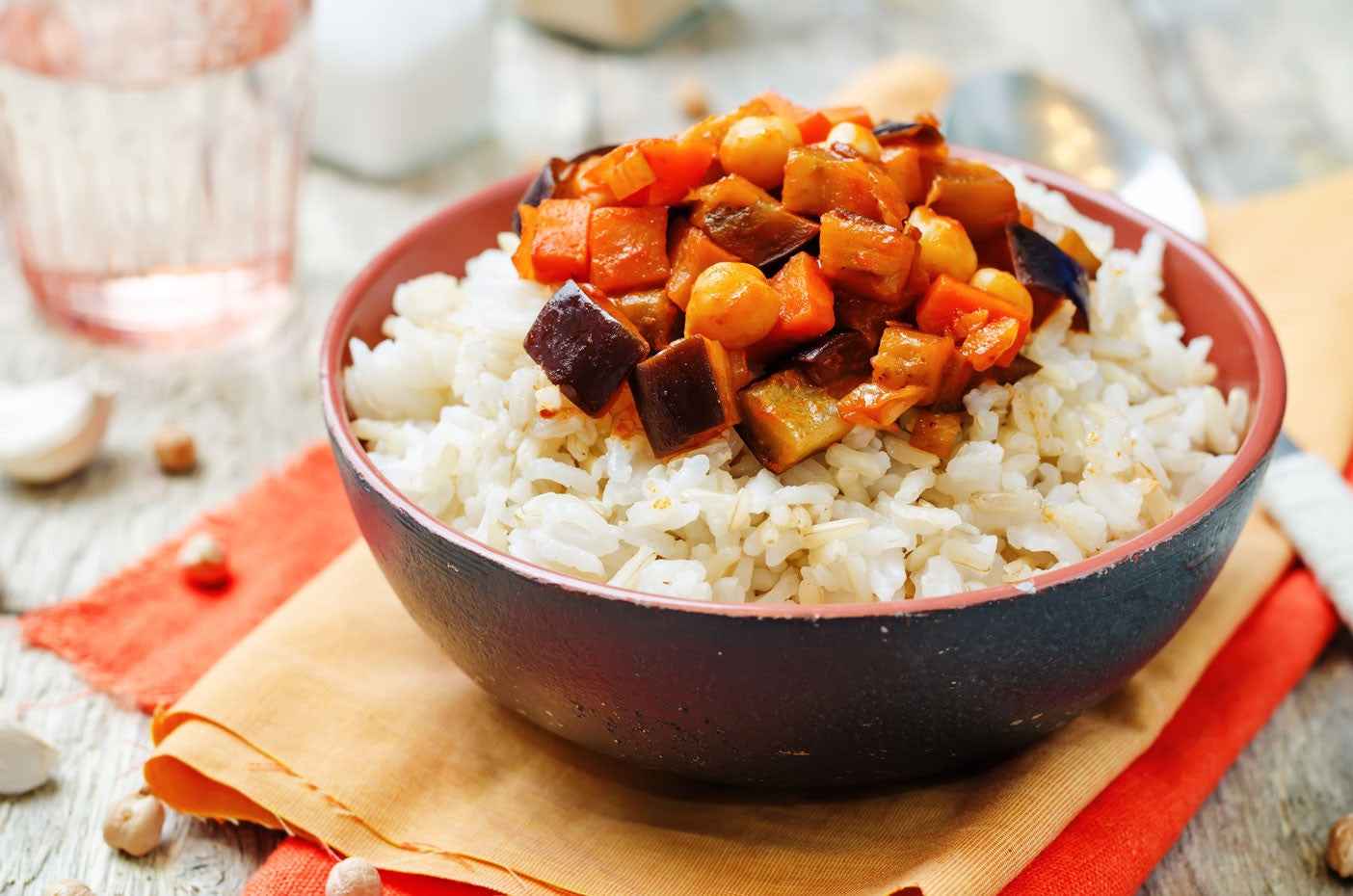 Bowl of rice and veggies on a table with orange napkin