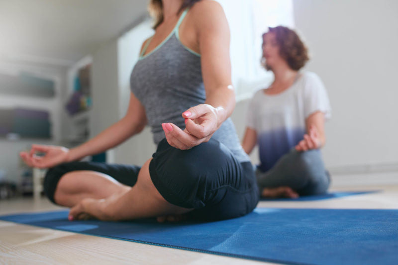 Two women sitting in meditation in yoga studio
