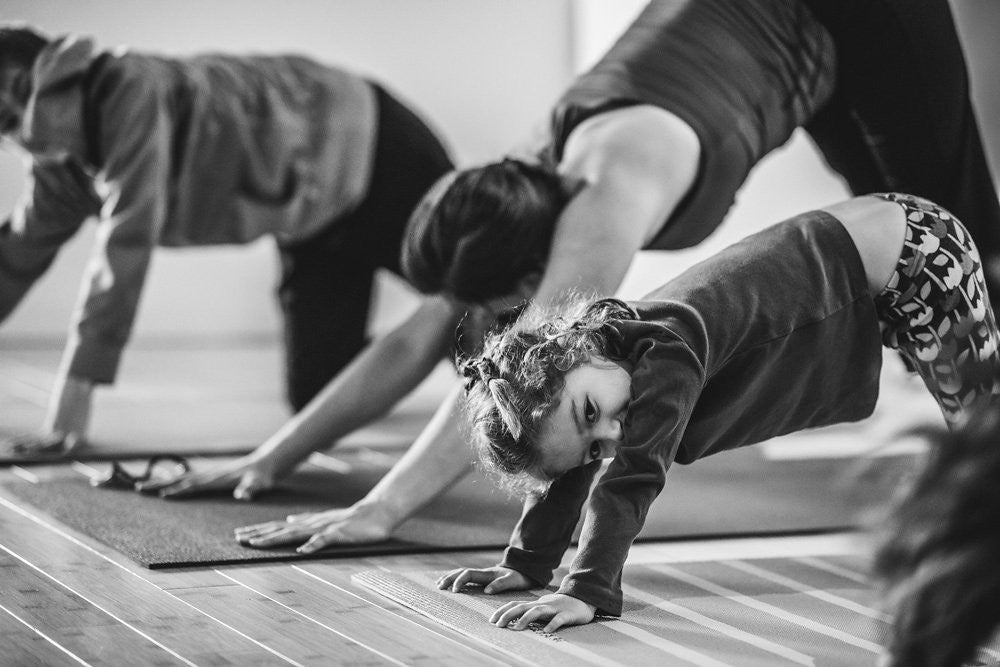 Kids and adults doing downward dog