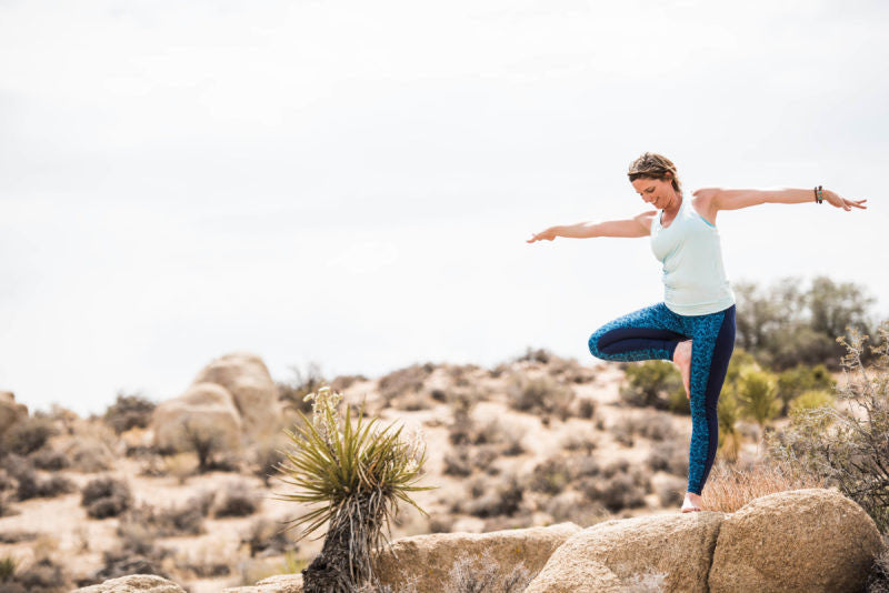 women plays in tree pose outside in desert