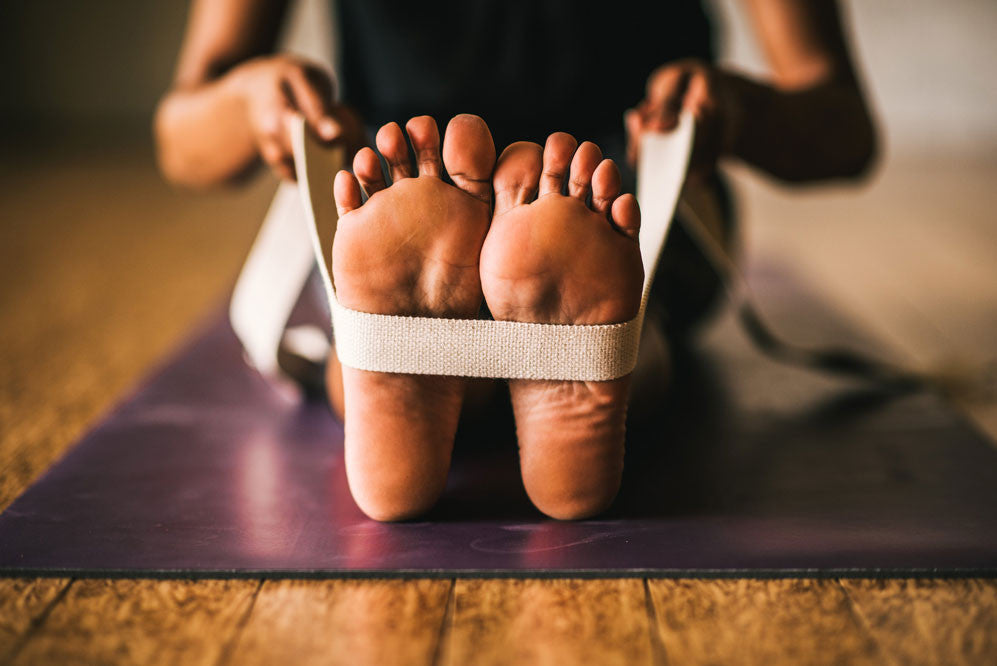 Yogi using yoga strap around feet