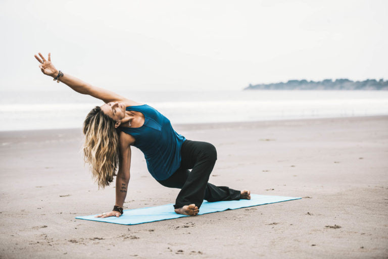 Woman doing yoga on the beach 