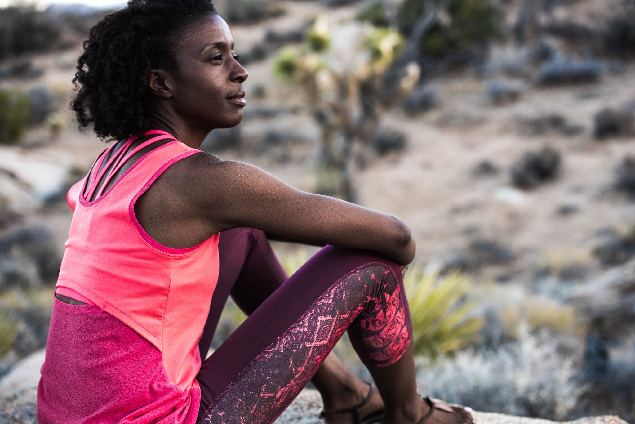 Woman pondering on a rock in workout clothes
