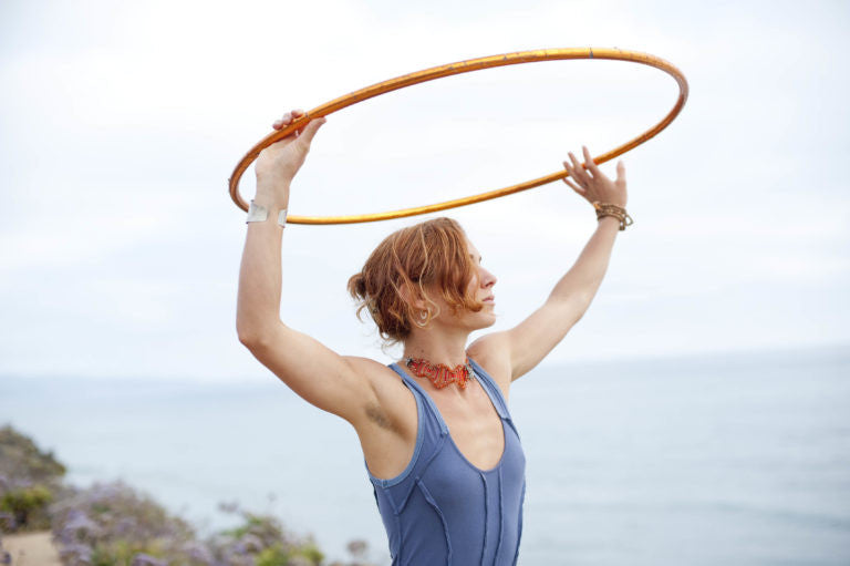 Woman holding a hula hoop above on her head on the beach