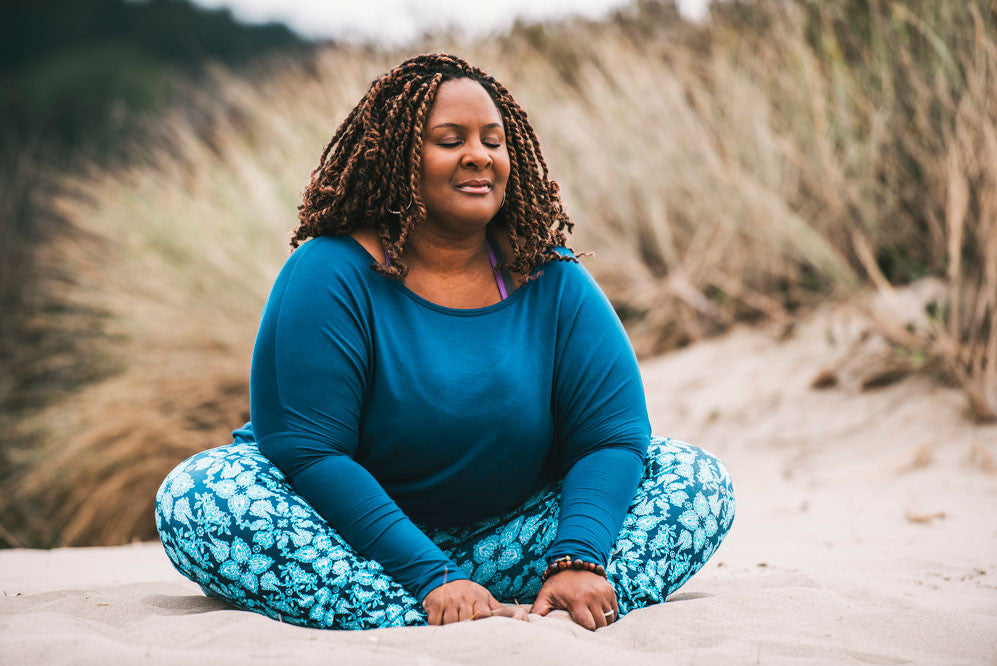 Woman seated in meditation on beach