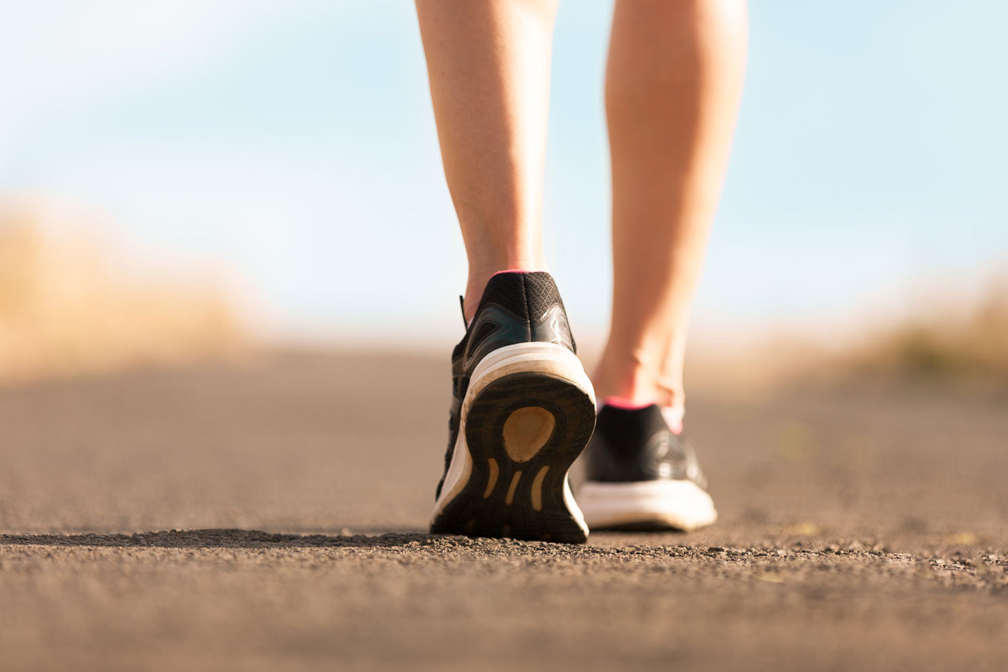 Woman walking on paved road in sneakers