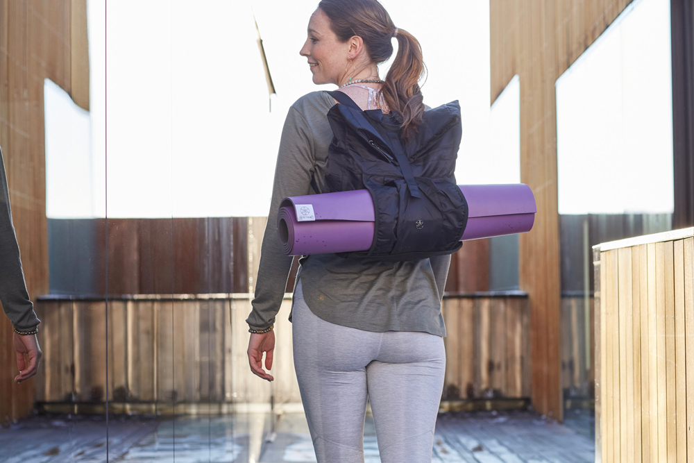 girl walking with backpack carrying yoga mat