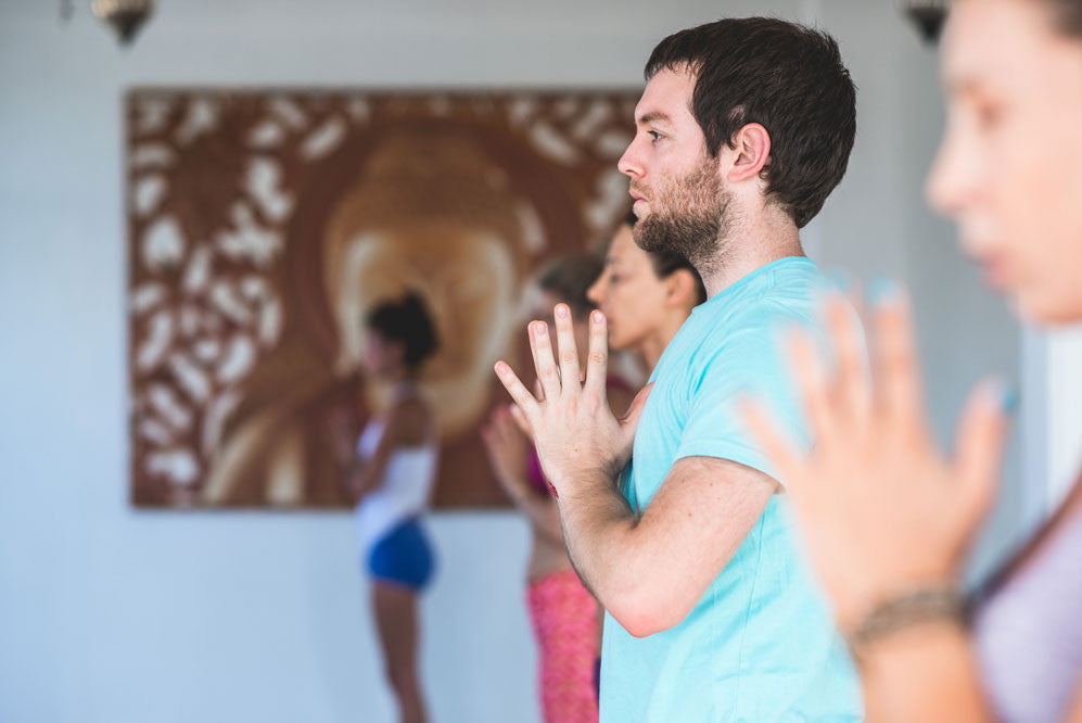 People stand in tadasana with hands at heart center in yoga