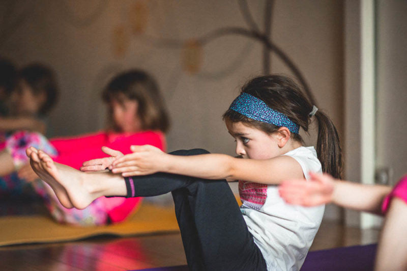 kids do boat pose in a kids yoga class