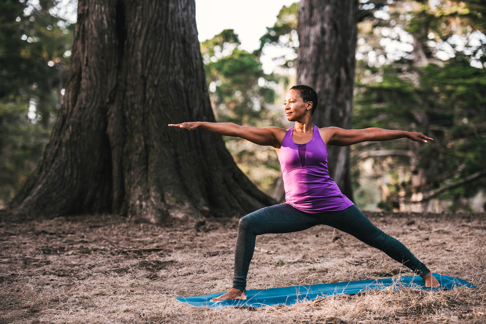woman does warrior 2 pose in the forest