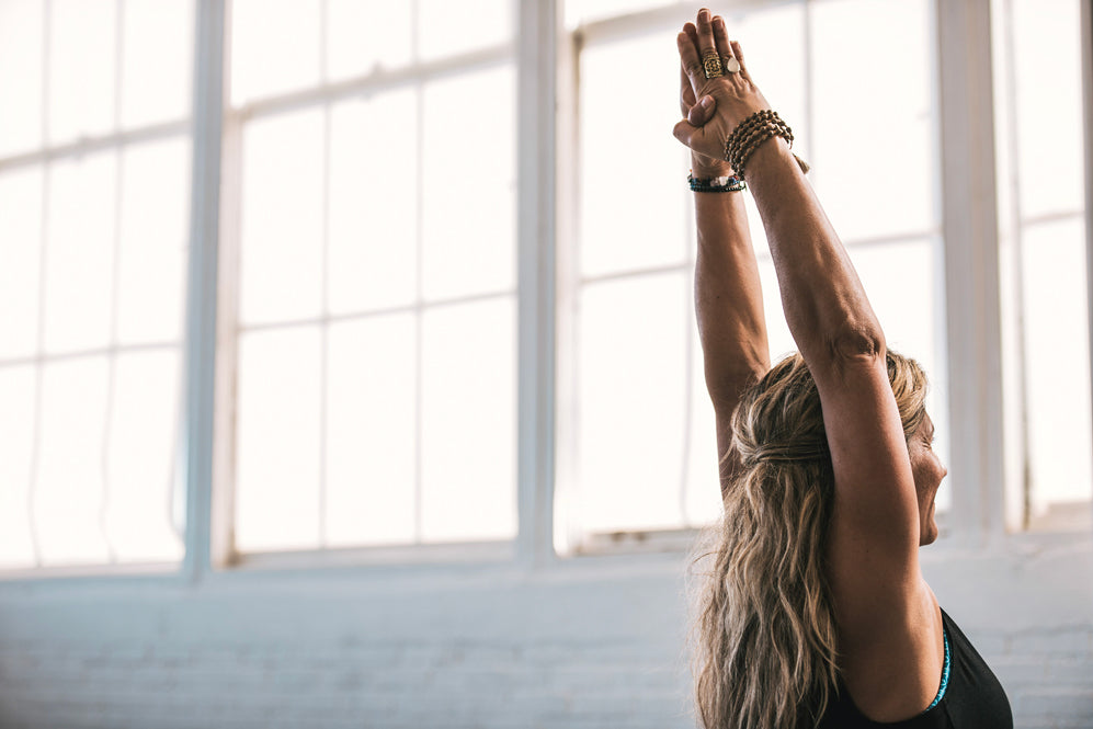 woman reaches arms above head during yoga
