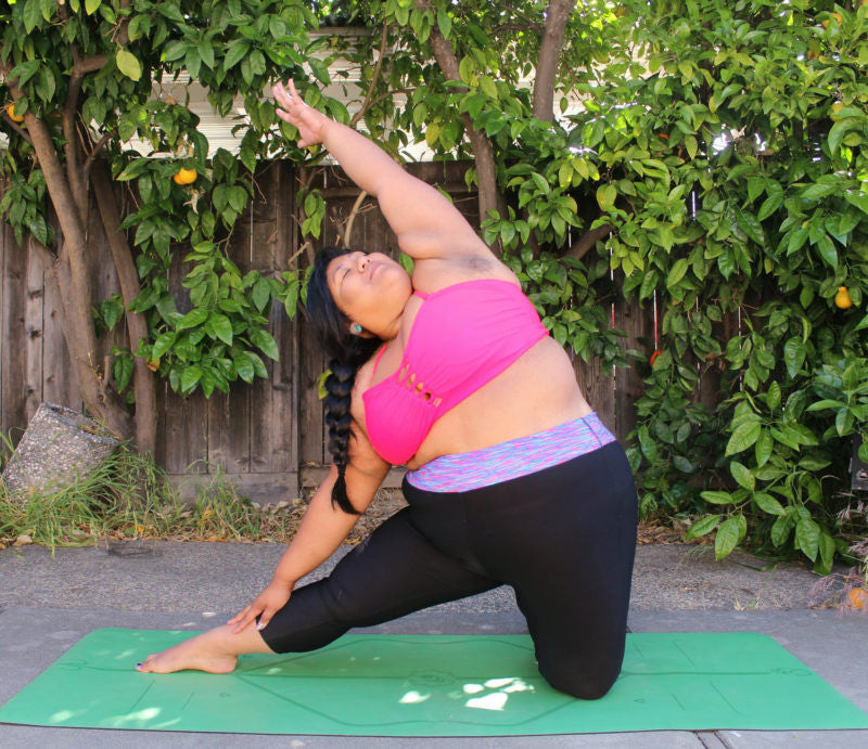 woman does a side stretch outside on yoga mat
