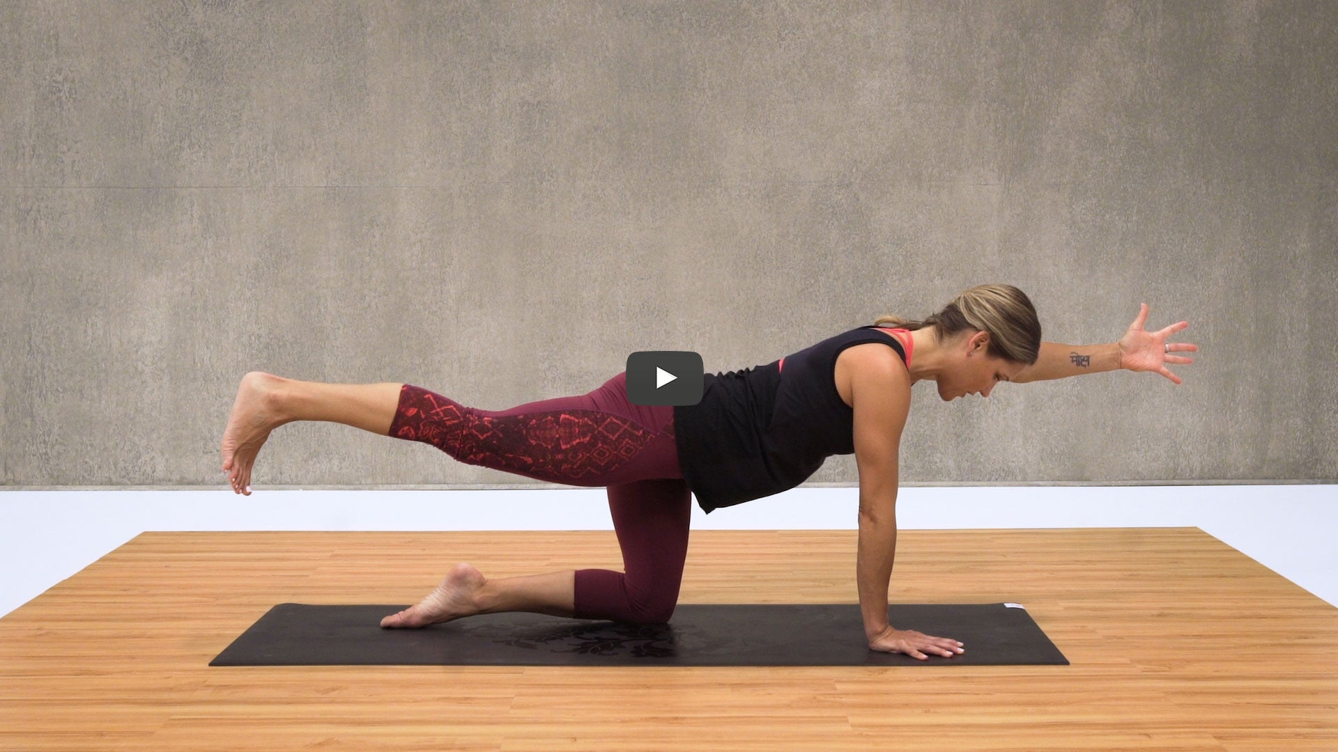 woman extends arm and leg on yoga mat