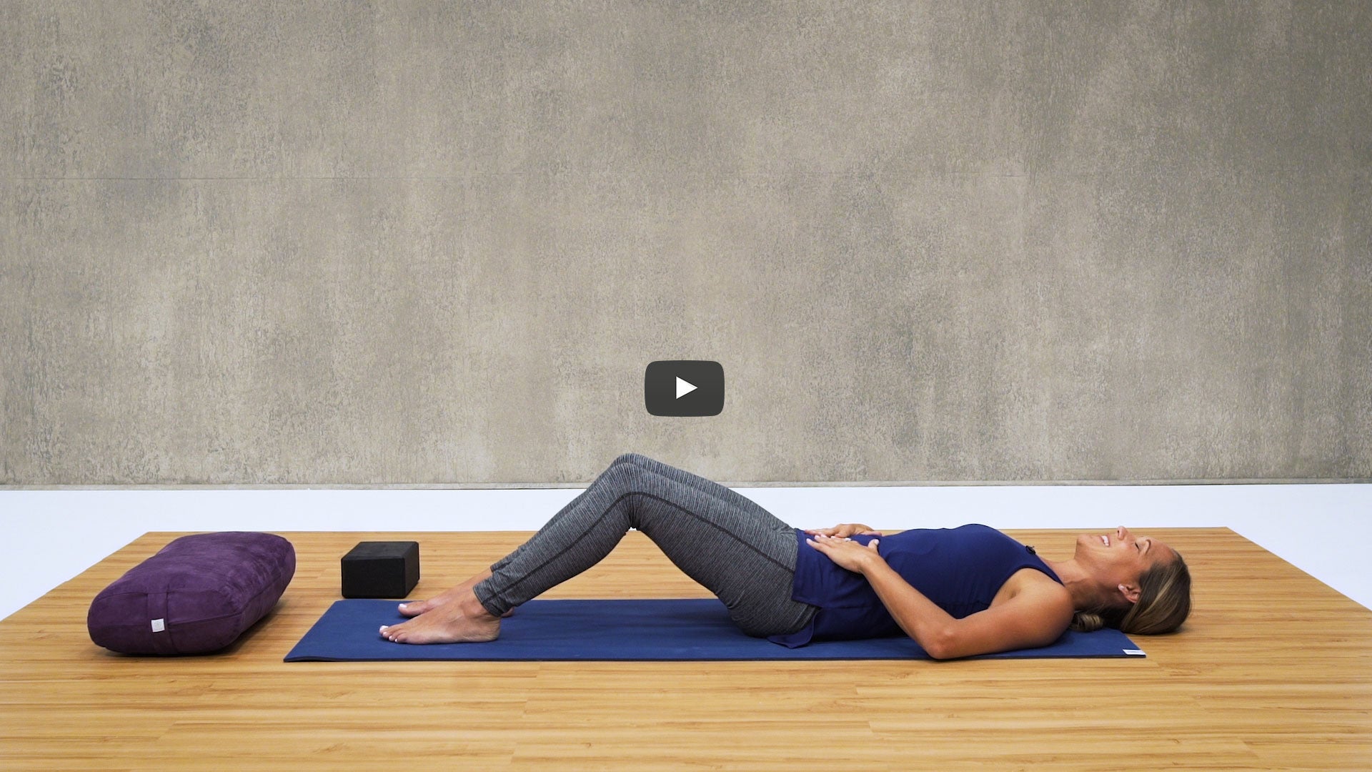 woman lays on yoga mat with bent knees