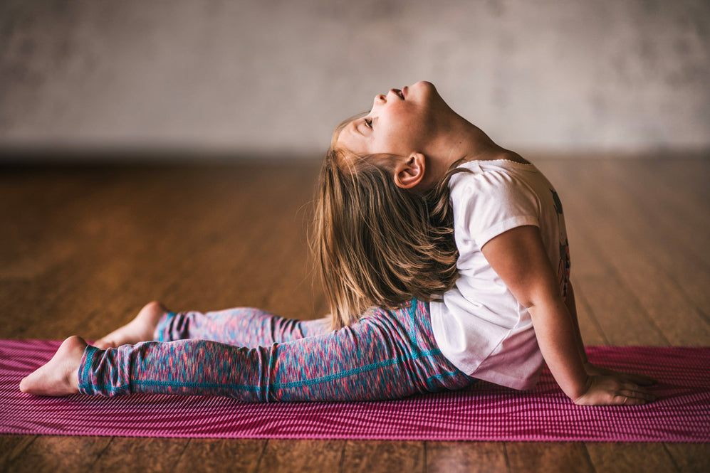 young girl does upward facing dog on a kids yoga mat