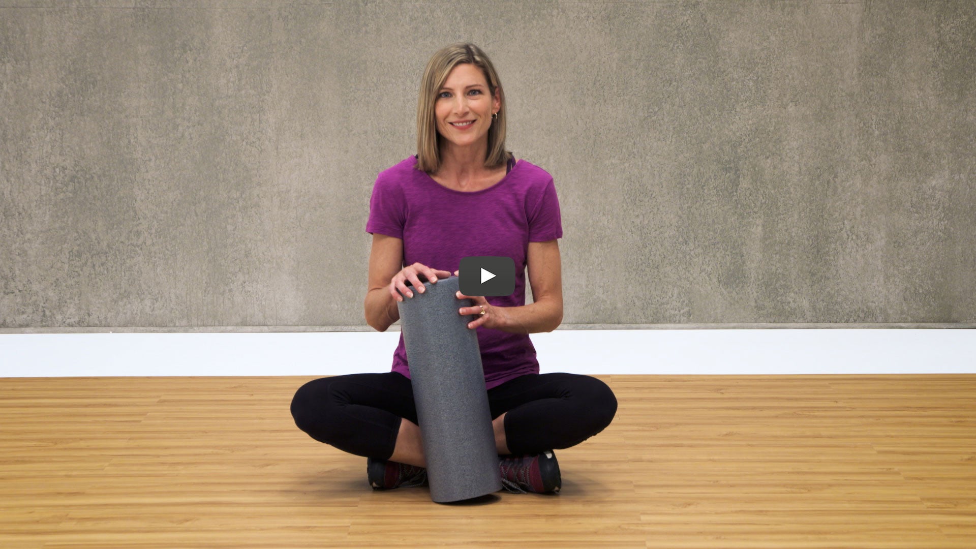 Woman holding a grey foam roller