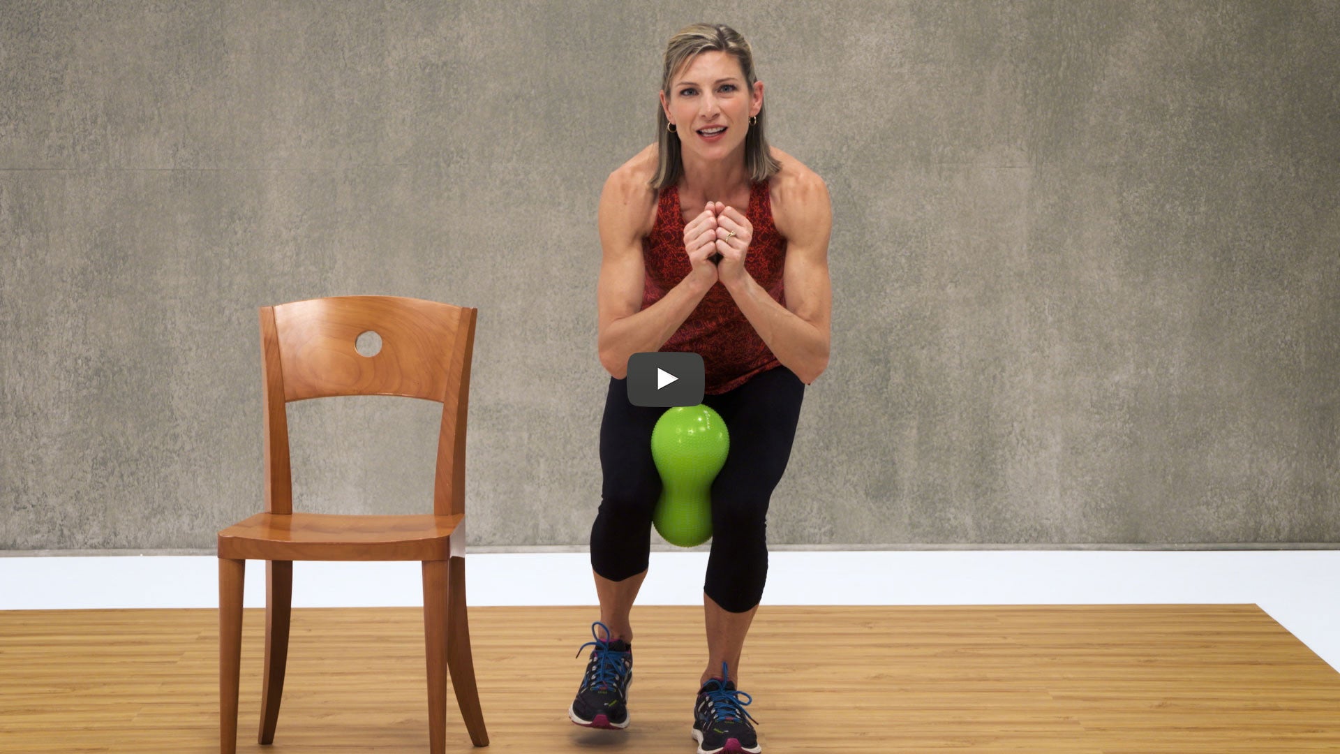 woman does back and core exercise squatted next to chair
