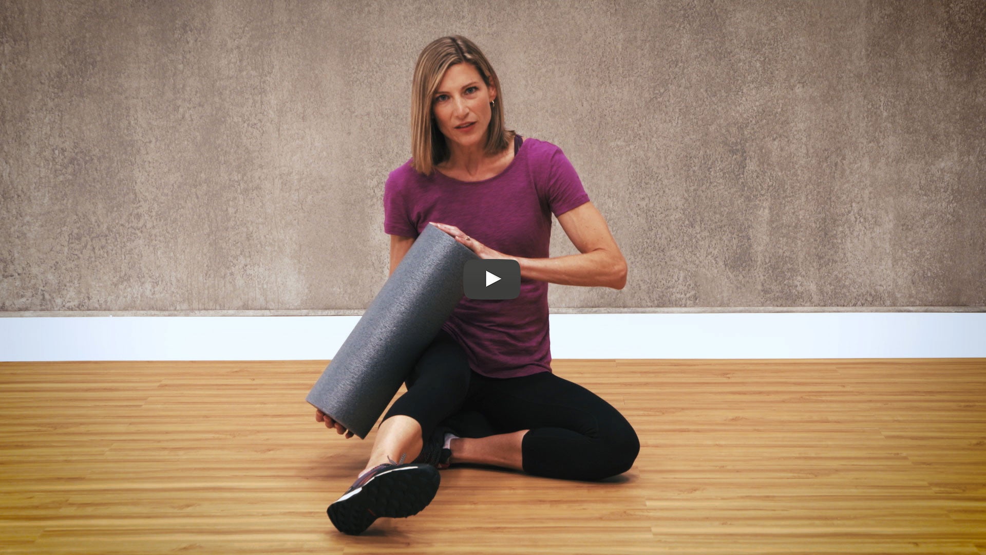 woman holds grey foam roller