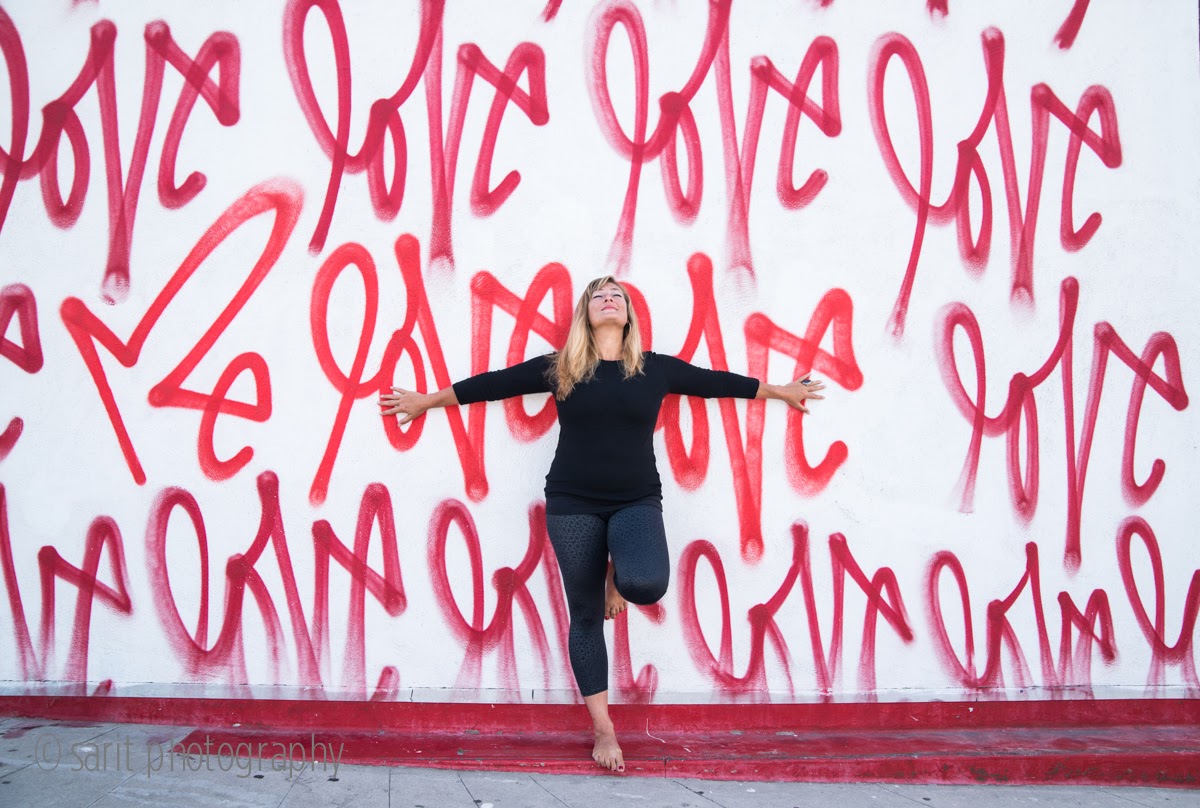 Blonde woman standing in front of a wall with words love spray painted all over