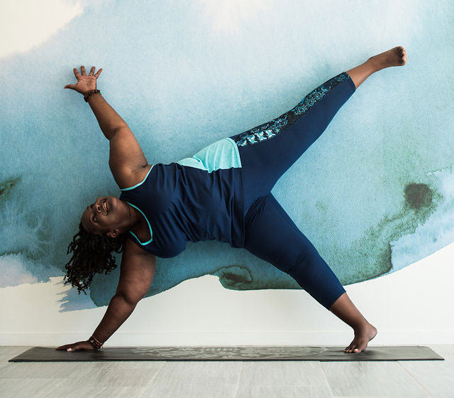 Woman does a balancing yoga pose against a wall