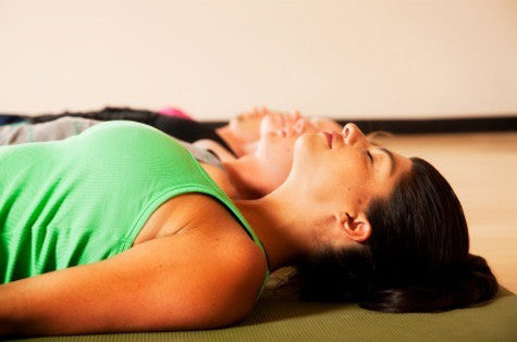 women lie in savasana in yoga class