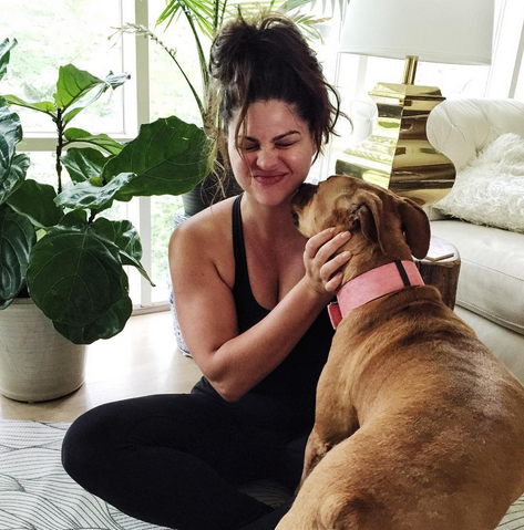 woman makes funny face while being licked by her dog
