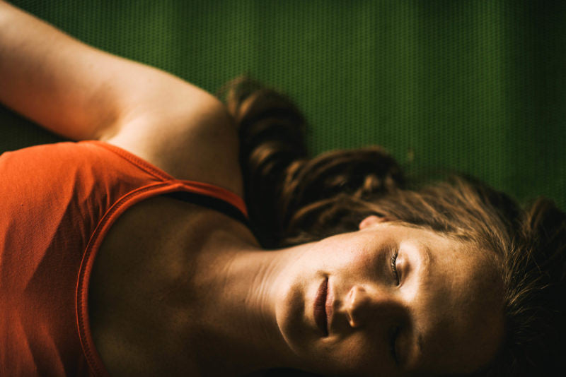 woman with eyes closed lays in savasana